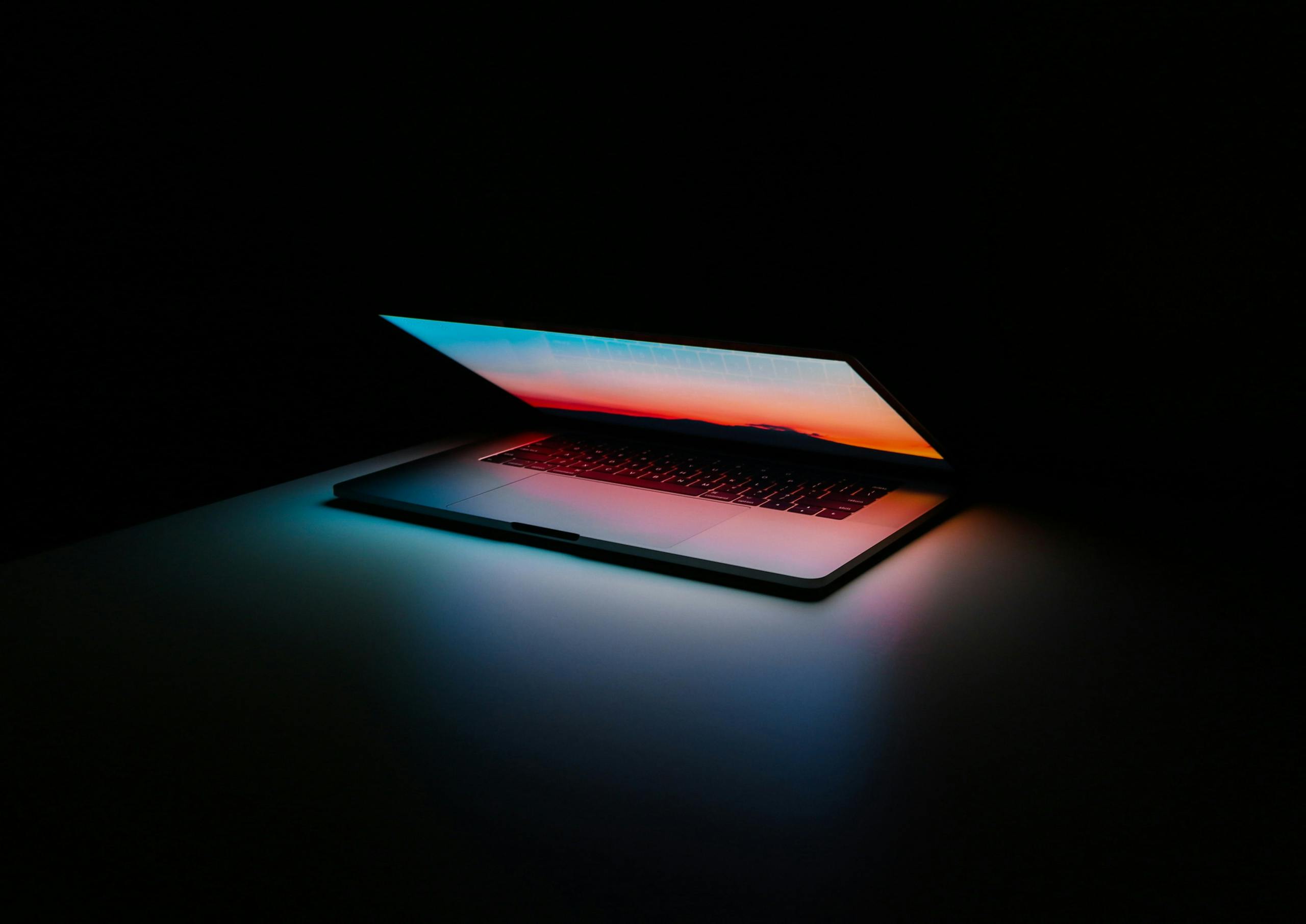 mac computer opening to show a glow of color
