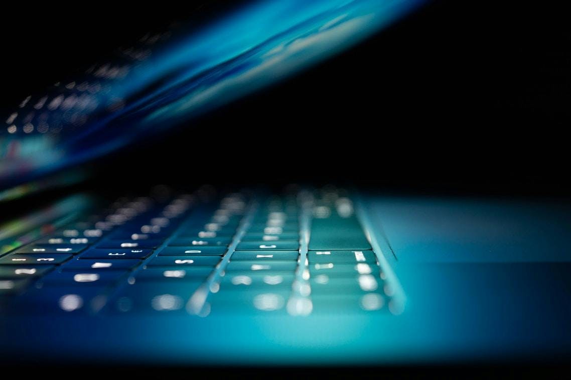 Close-up of a laptop keyboard, lit in blue