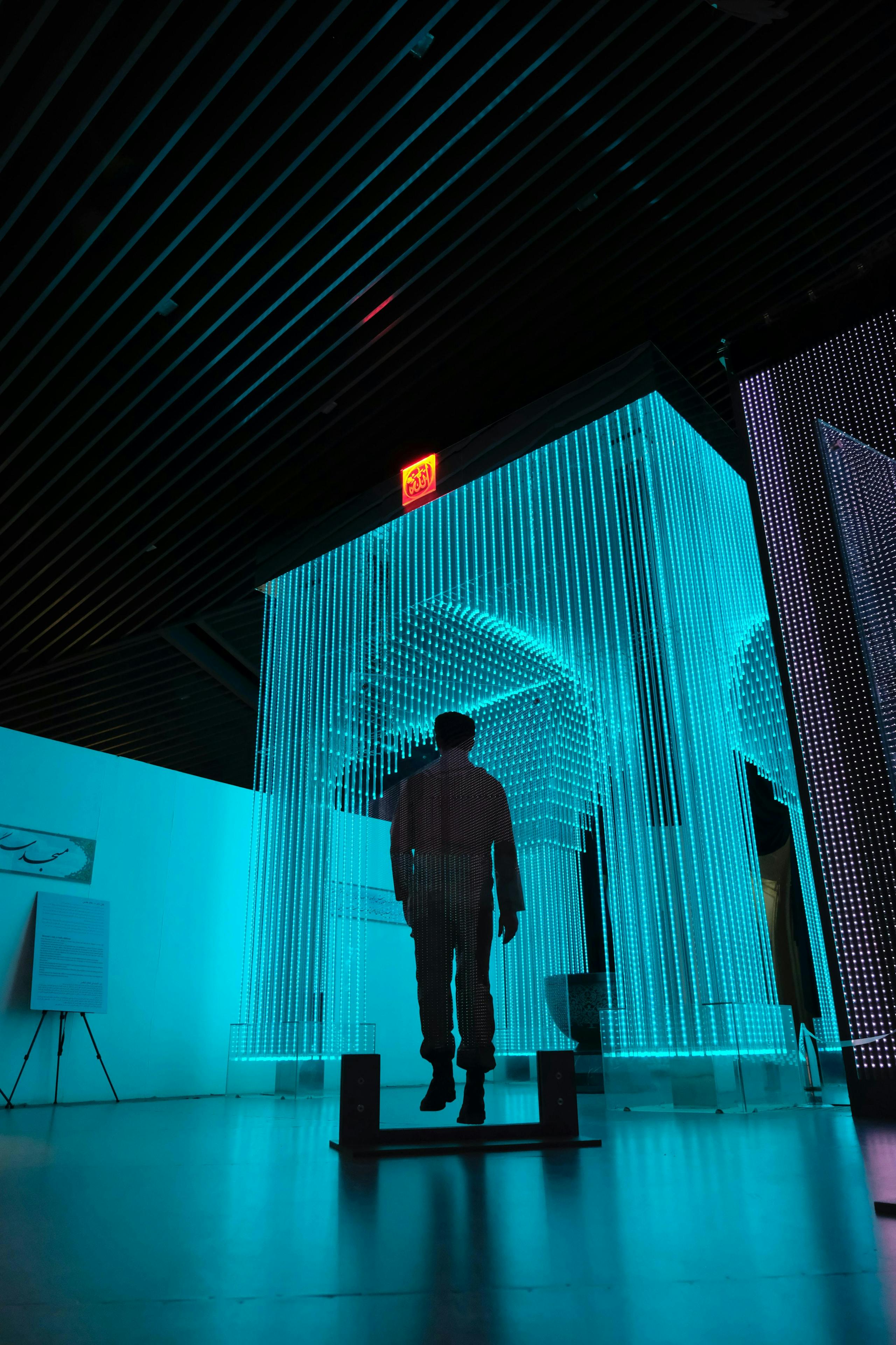 Man standing in an art display lit in blue light